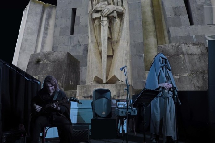 Presentación de Alejandro Miniaci y Paola Salamone frente a la obra "El ángel guardián" -popularizada como "El ángel exterminador"-, en la entrada del cementerio de Azul.